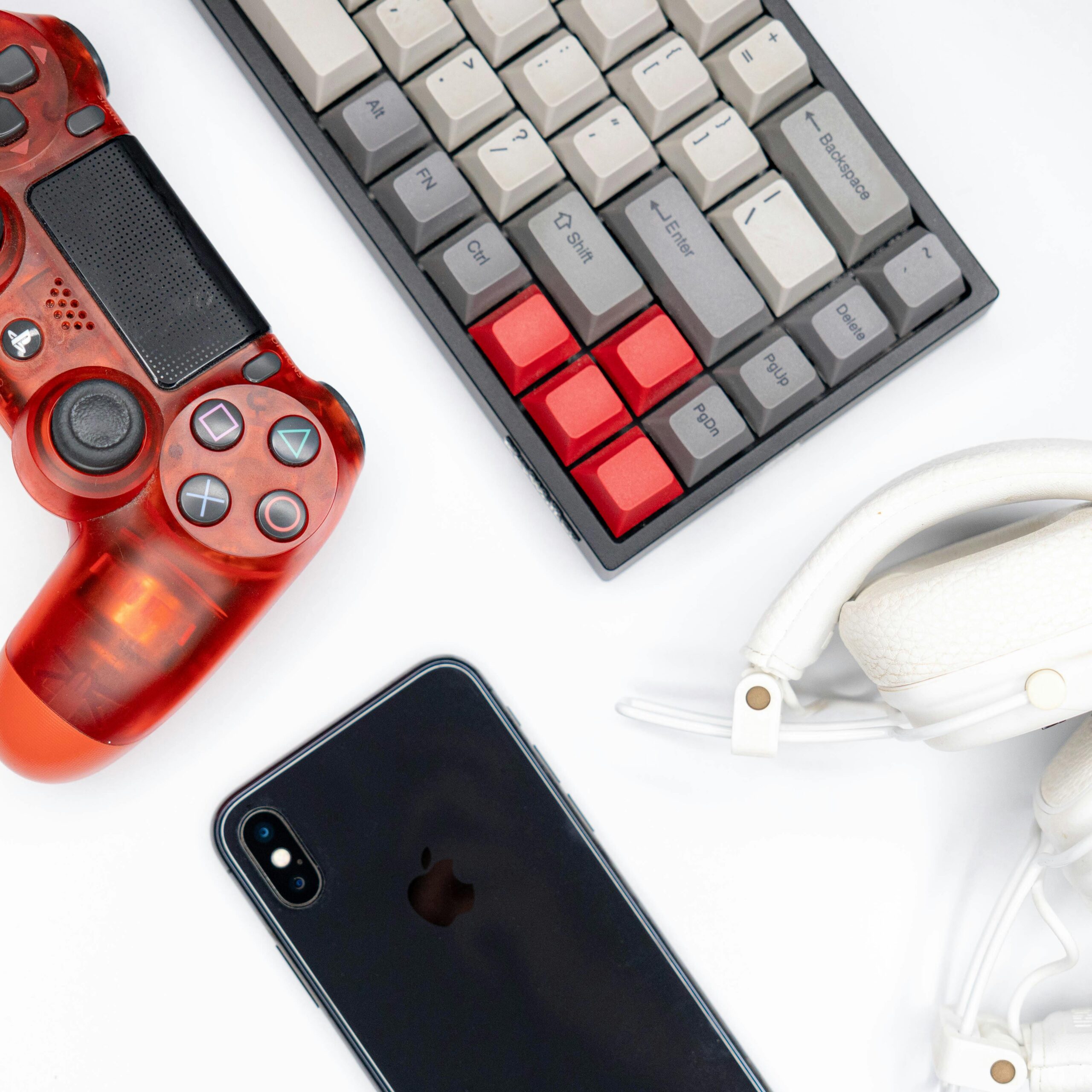 Top view of modern tech gadgets including gaming controller, smartphone, keyboard, and headphones.