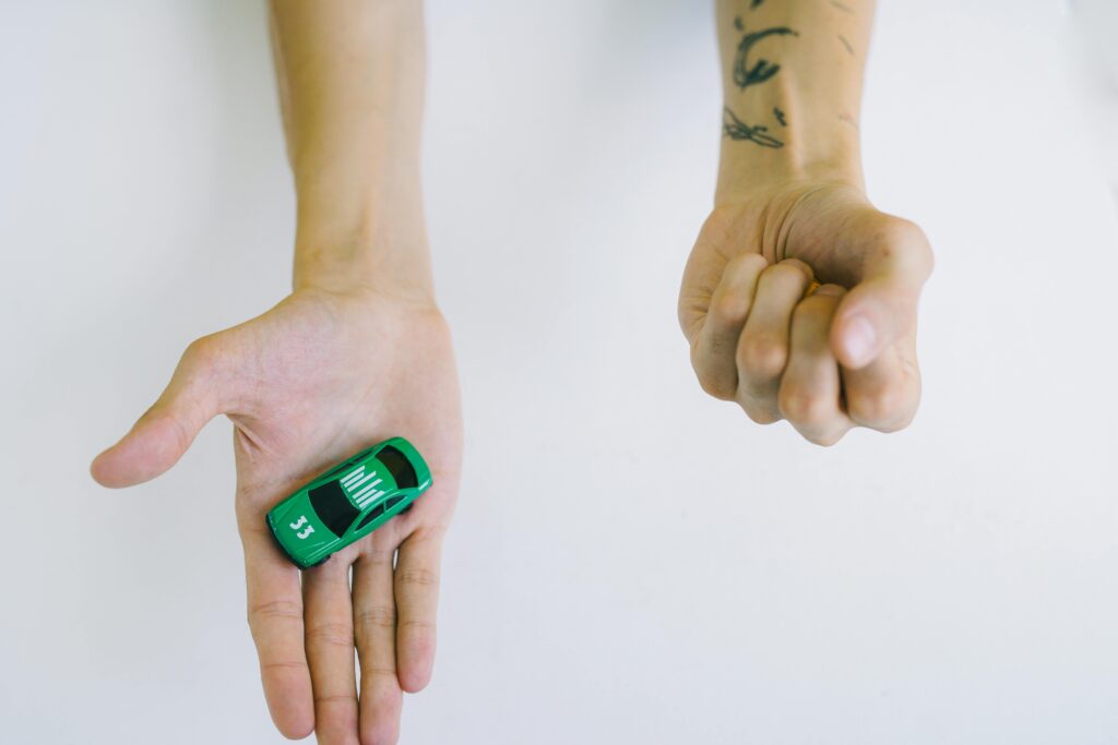 Close-up of hands holding a green toy car, symbolizing control and playfulness.